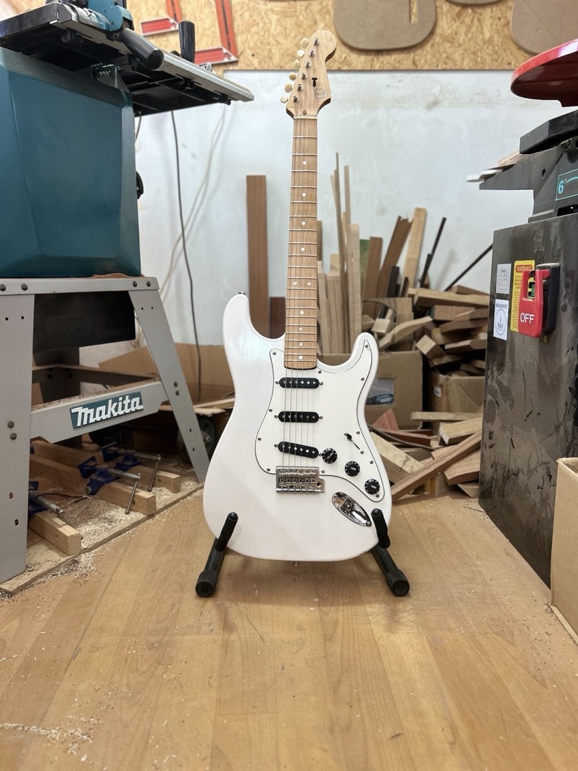 גיטרה חשמלית לבנה קאסטום על סטנד בסדנת DS Guitars